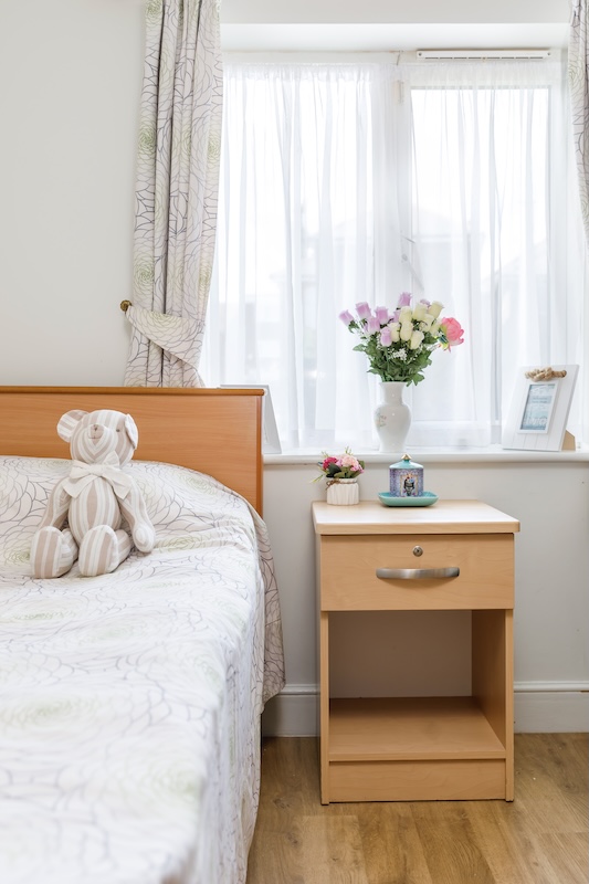 white bedroom with window and teddy on the bed